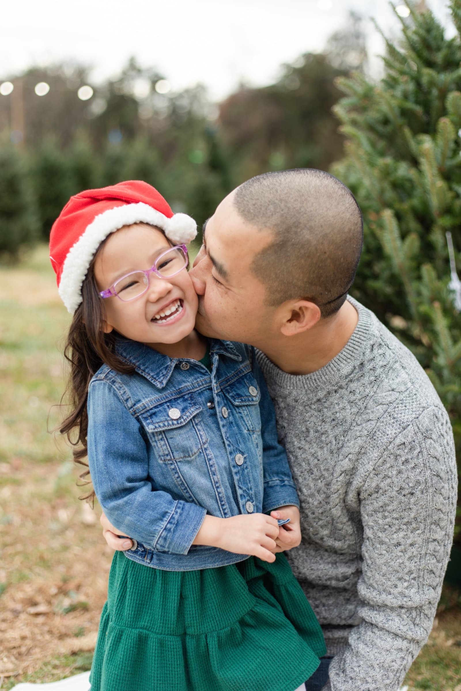Father kissing his laughing daughter in a Santa hat