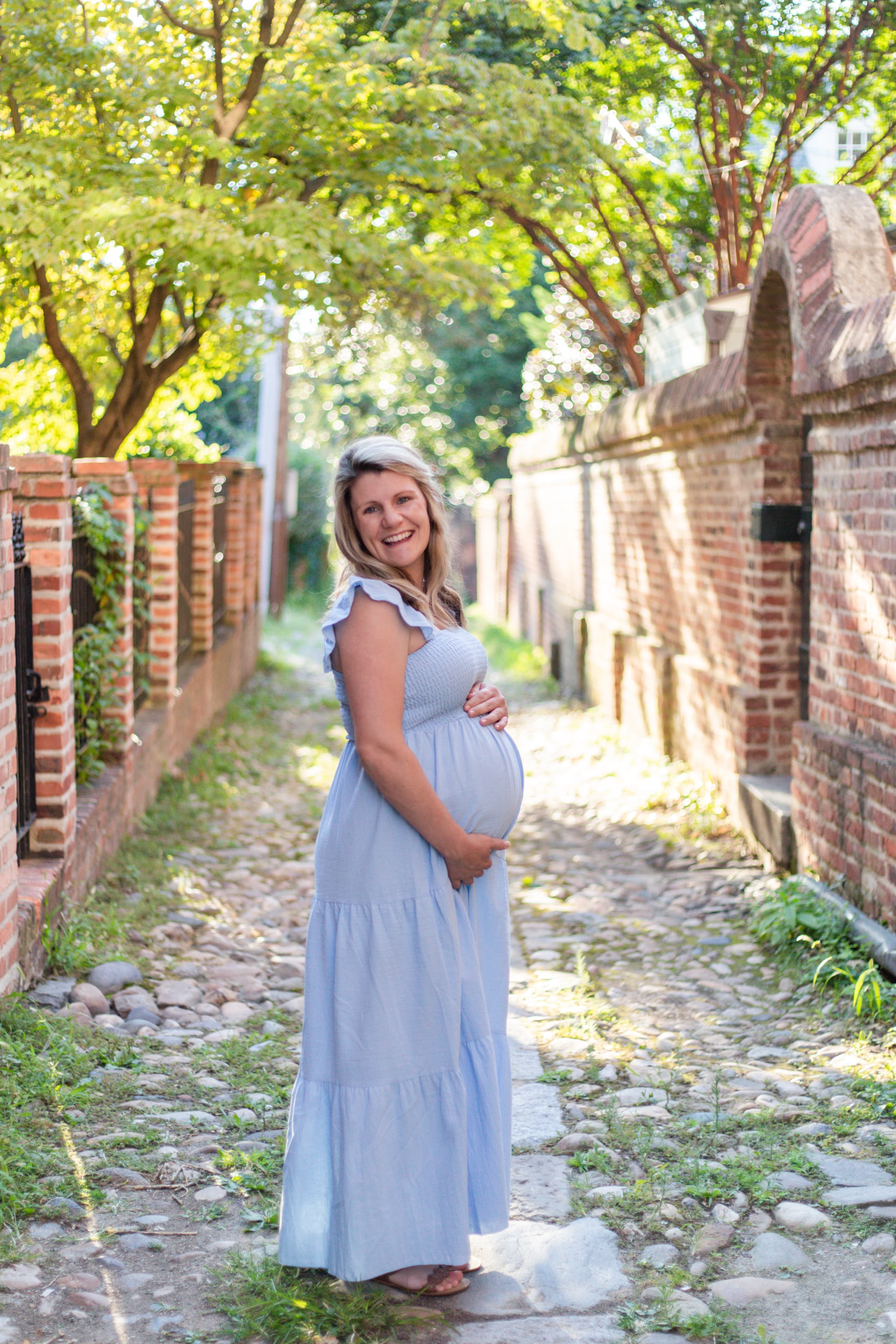 Expecting mother in blue cradling her belly