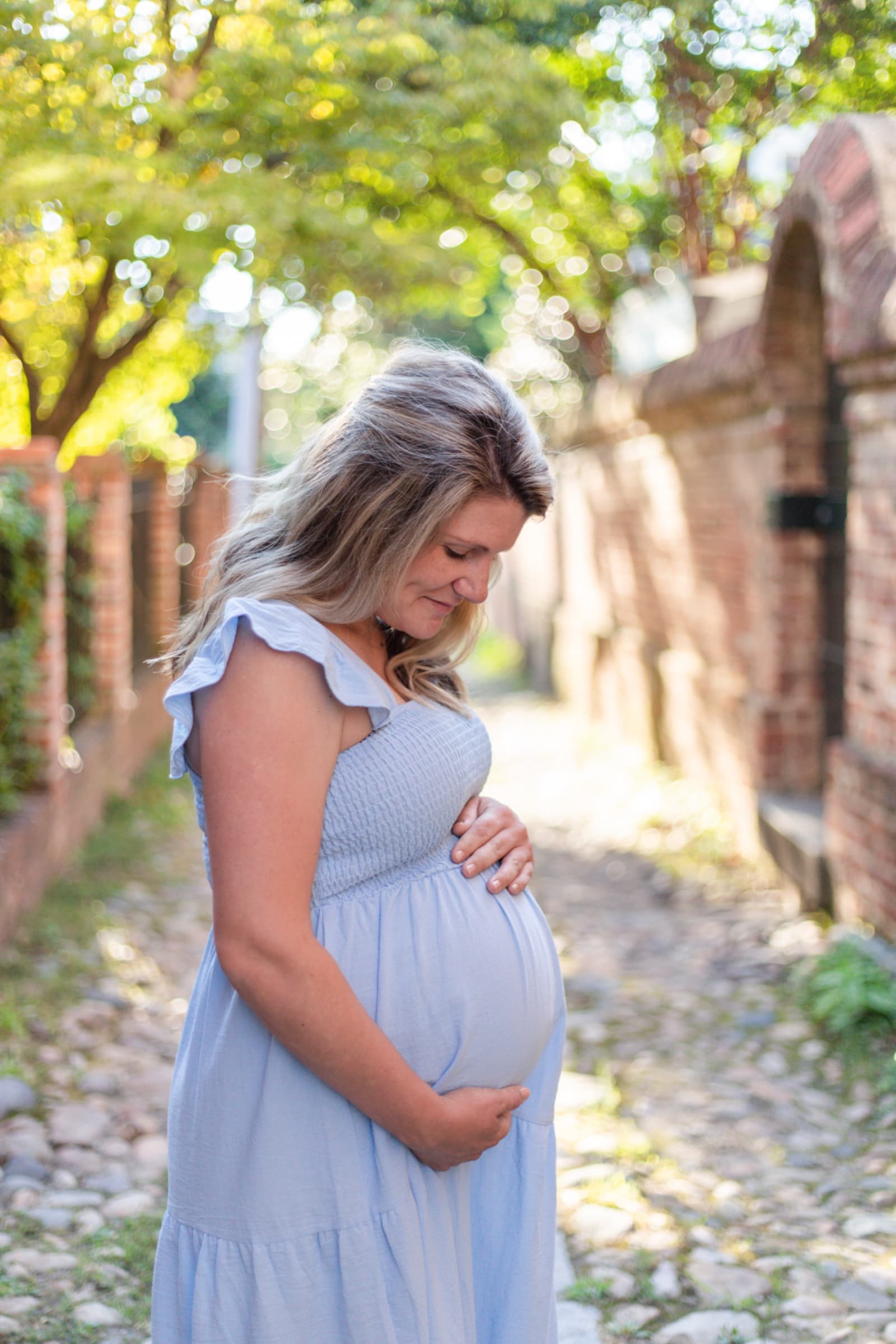 Expecting mother in blue cradling her belly, looking down