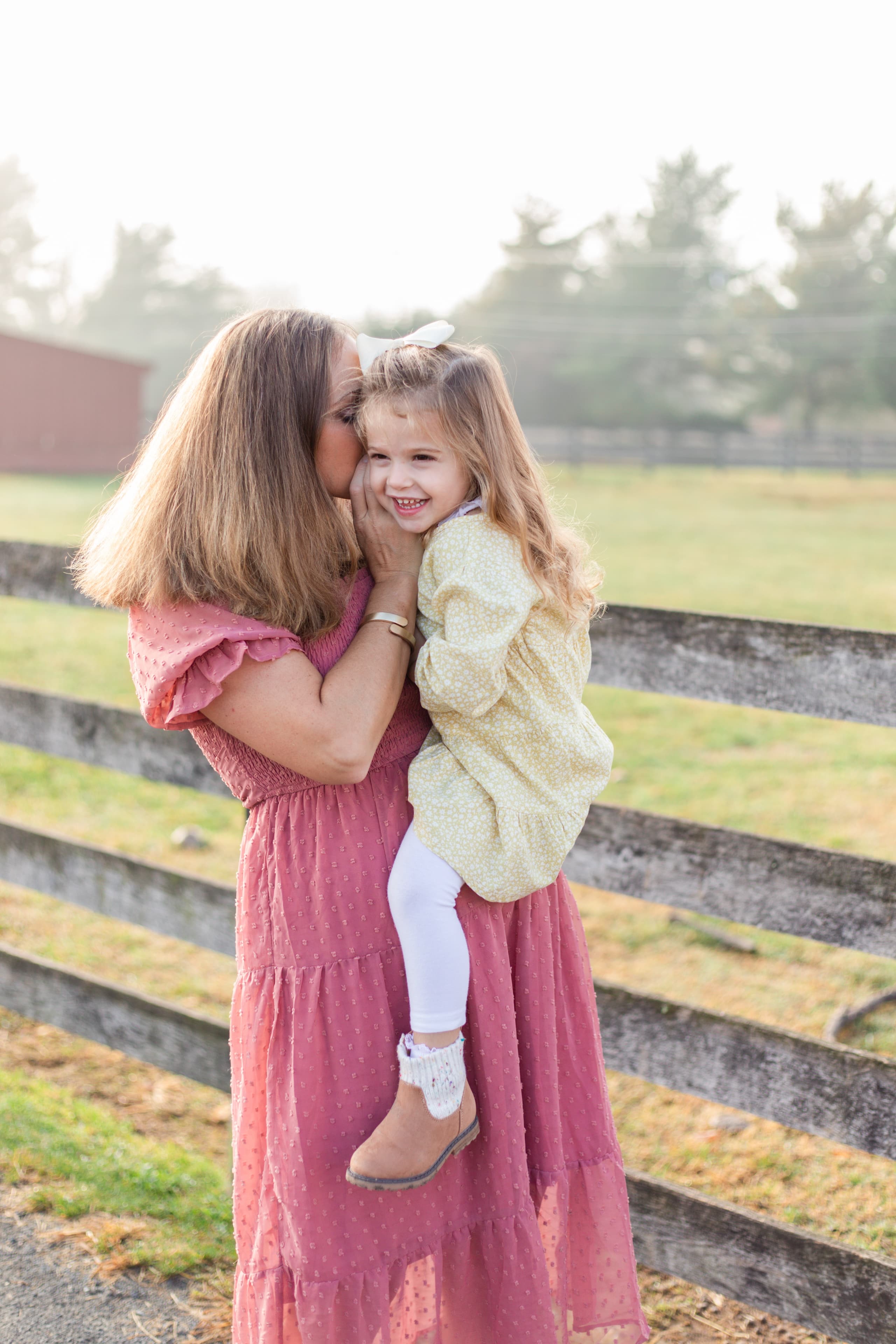 Mother and daughter in a foggy field at golden hour
